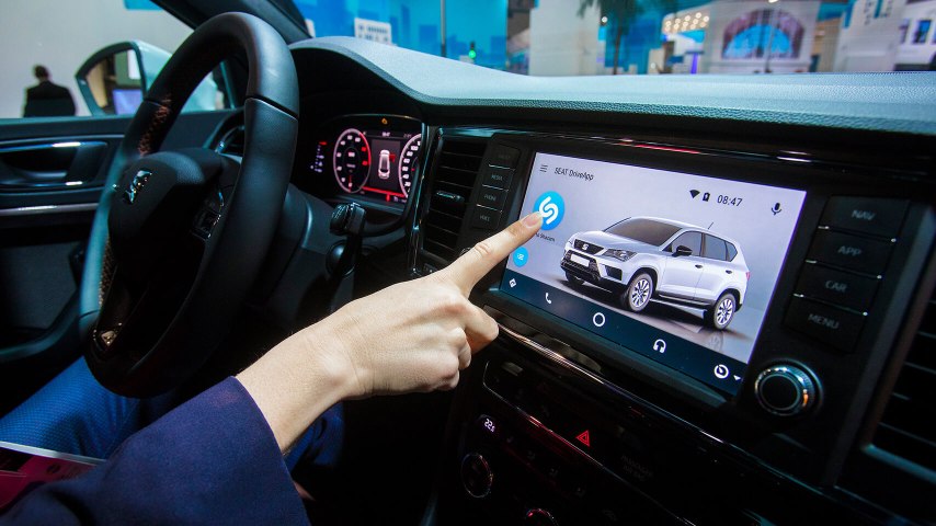 Finger touching the screen inside of a SEAT model with Shazam and SEAT DriveApp technology