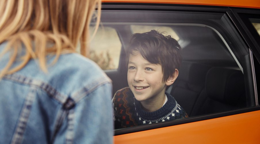 SEAT new car services and maintenance – Boy smiling inside a new car at a woman standing outside side view