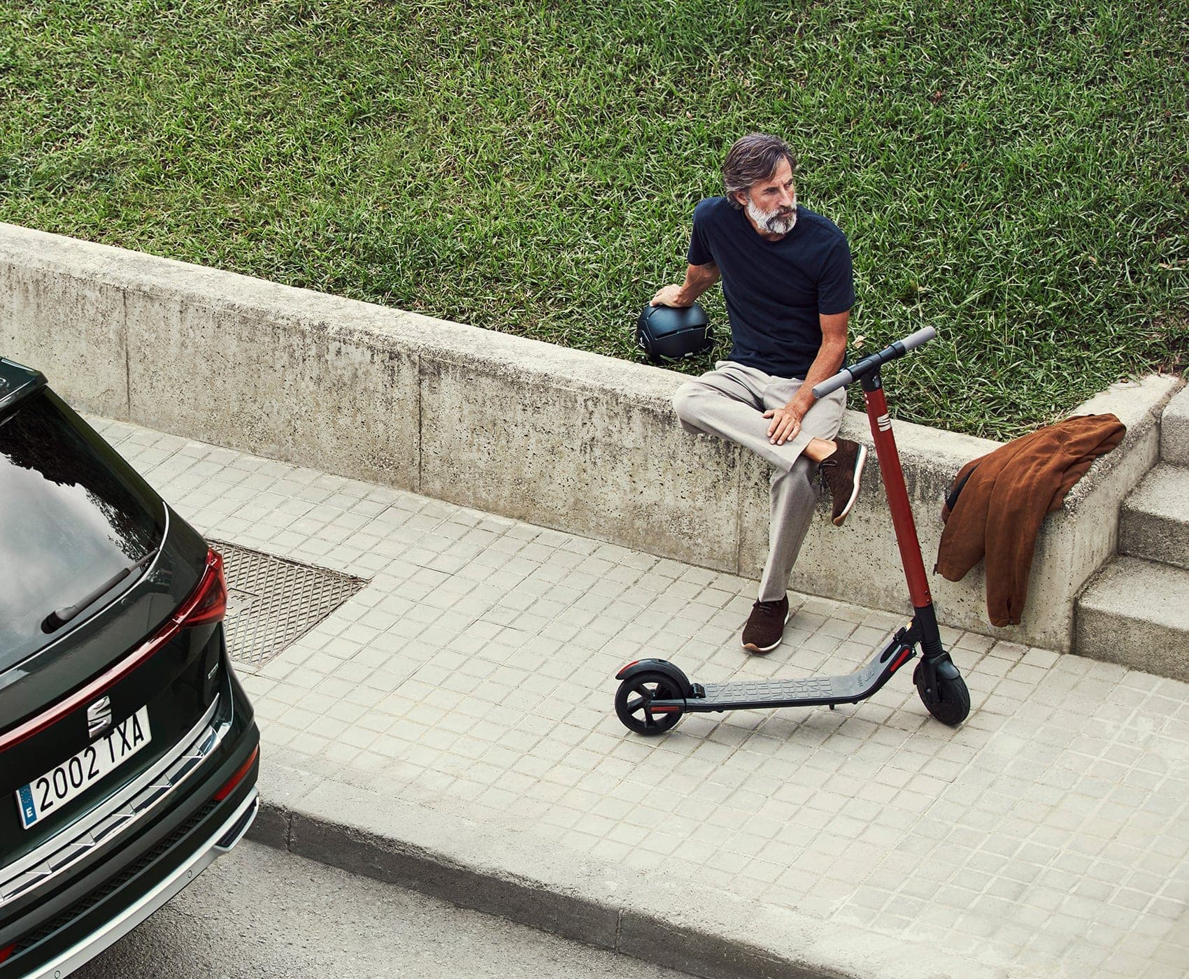 SEAT eXS KickScooter urban mobility solution powered by Segway - Man walking next to Tarraco large SUV