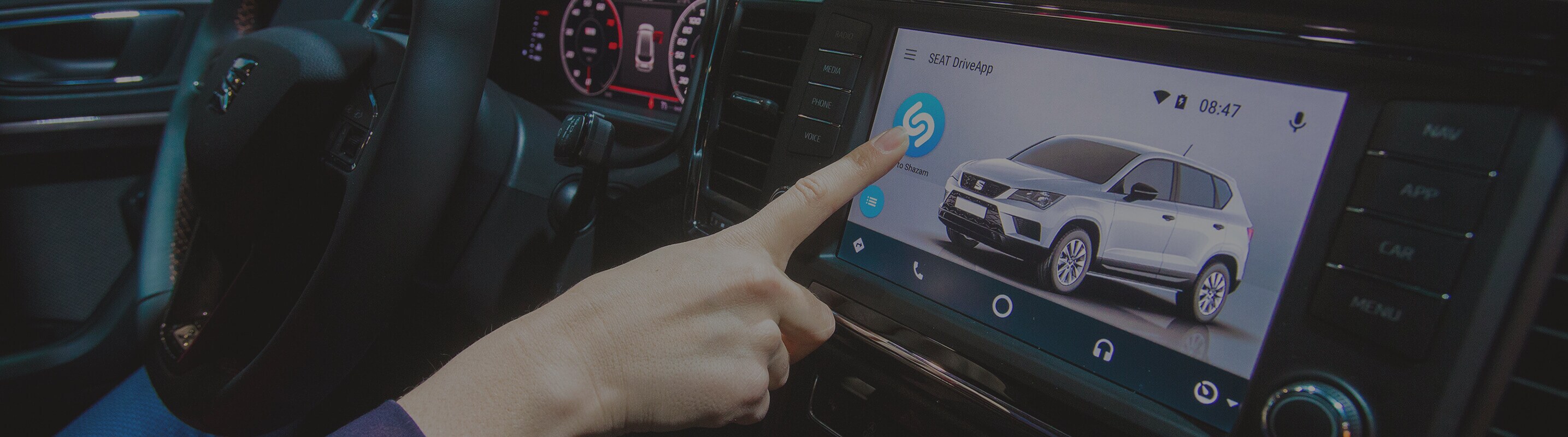 Finger touching the screen inside of a SEAT model with Shazam and SEAT DriveApp technology