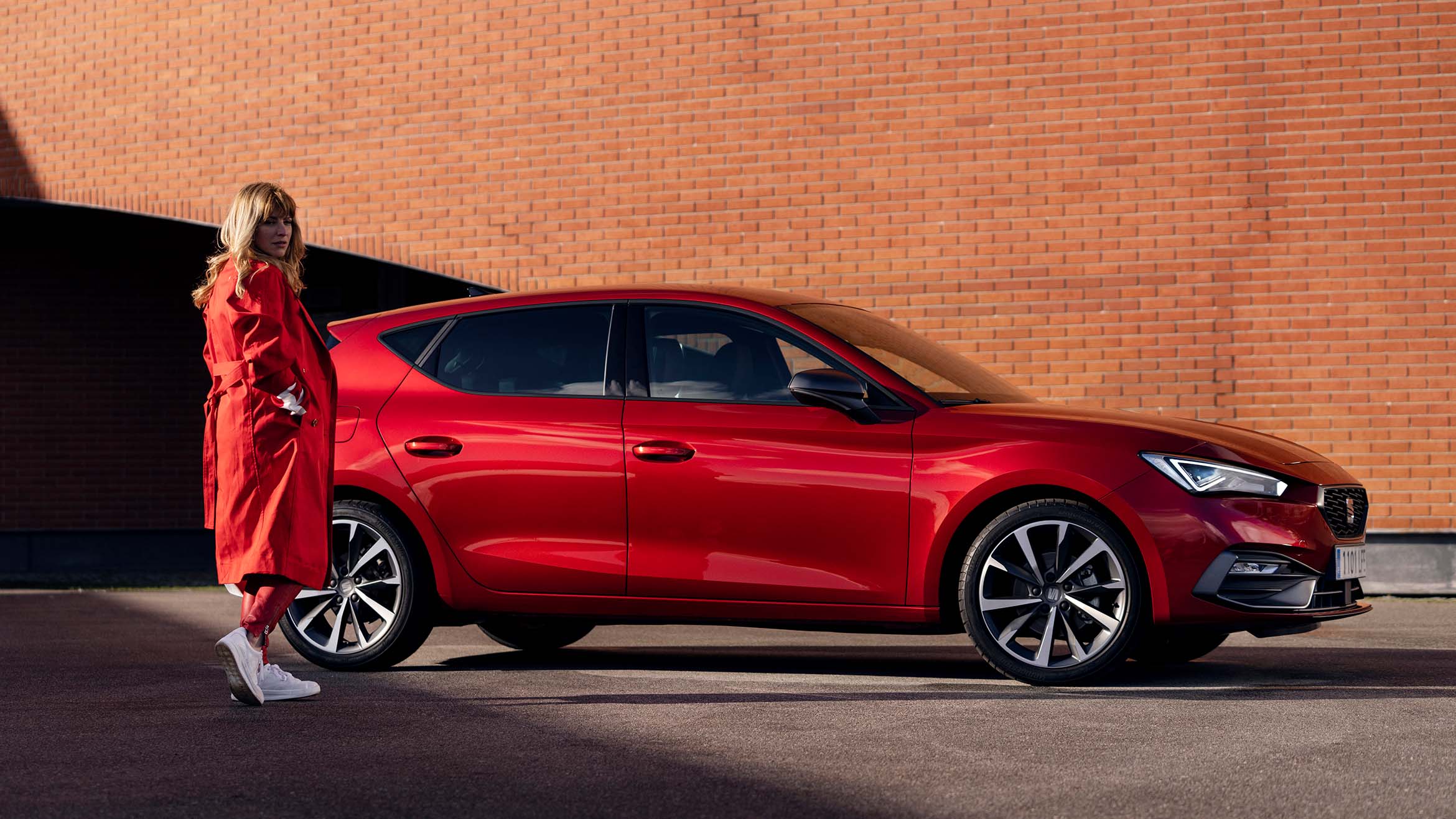 woman in a red coat standing next to seat leon desire red colour