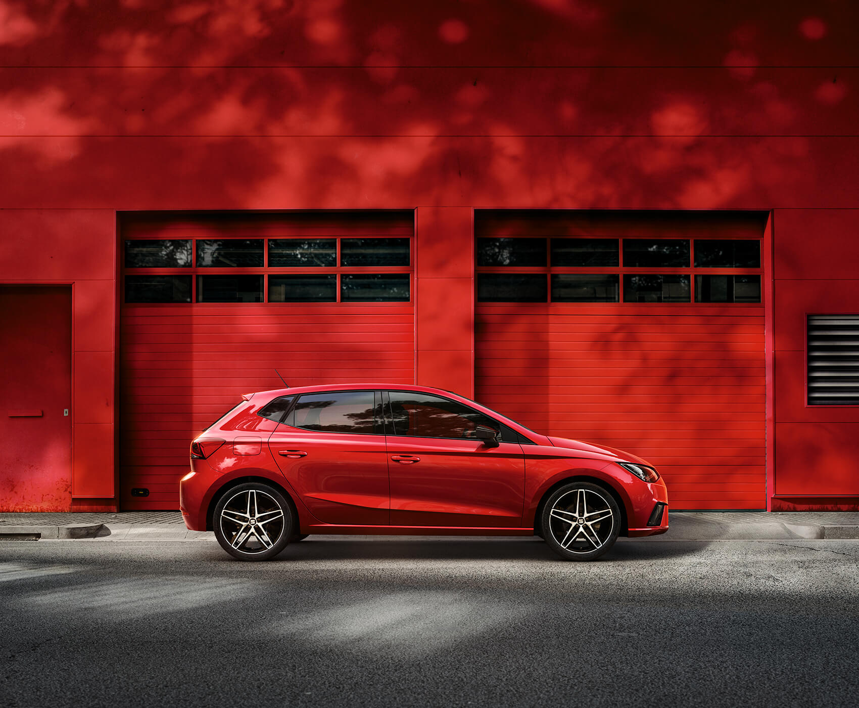 SEAT new car services maintenance independent garages – Red SEAT Ibiza city car hatchback parked in front of a red garage wall