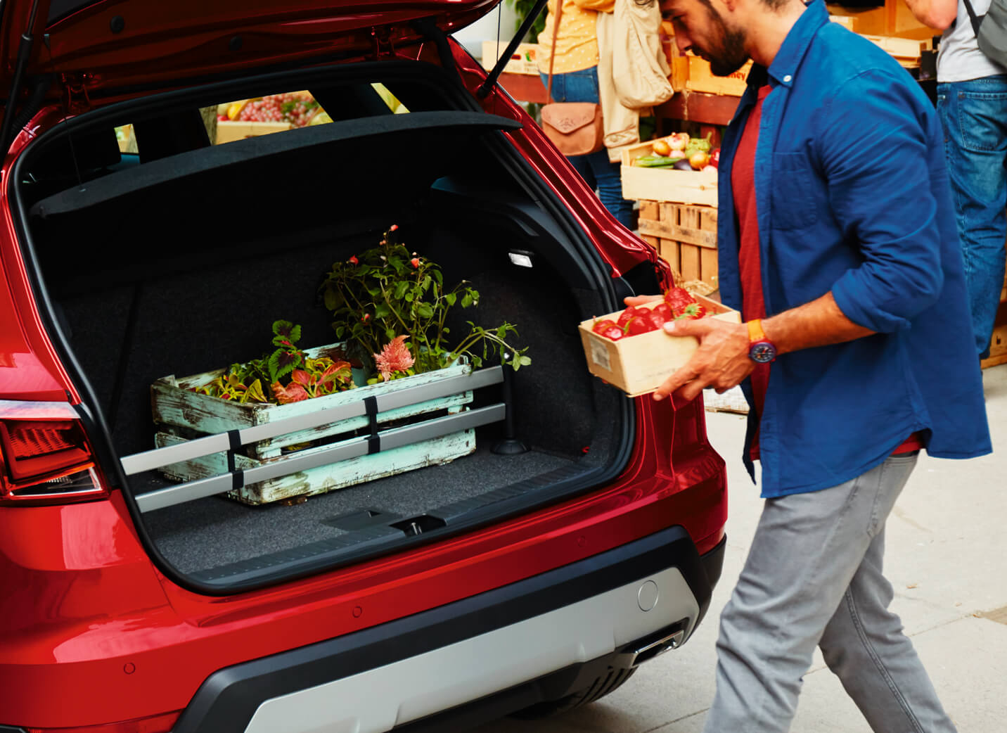 SEAT new car services accessories maintenance – man using the spacious boot of the SEAT Arona crossover SUV for flowers