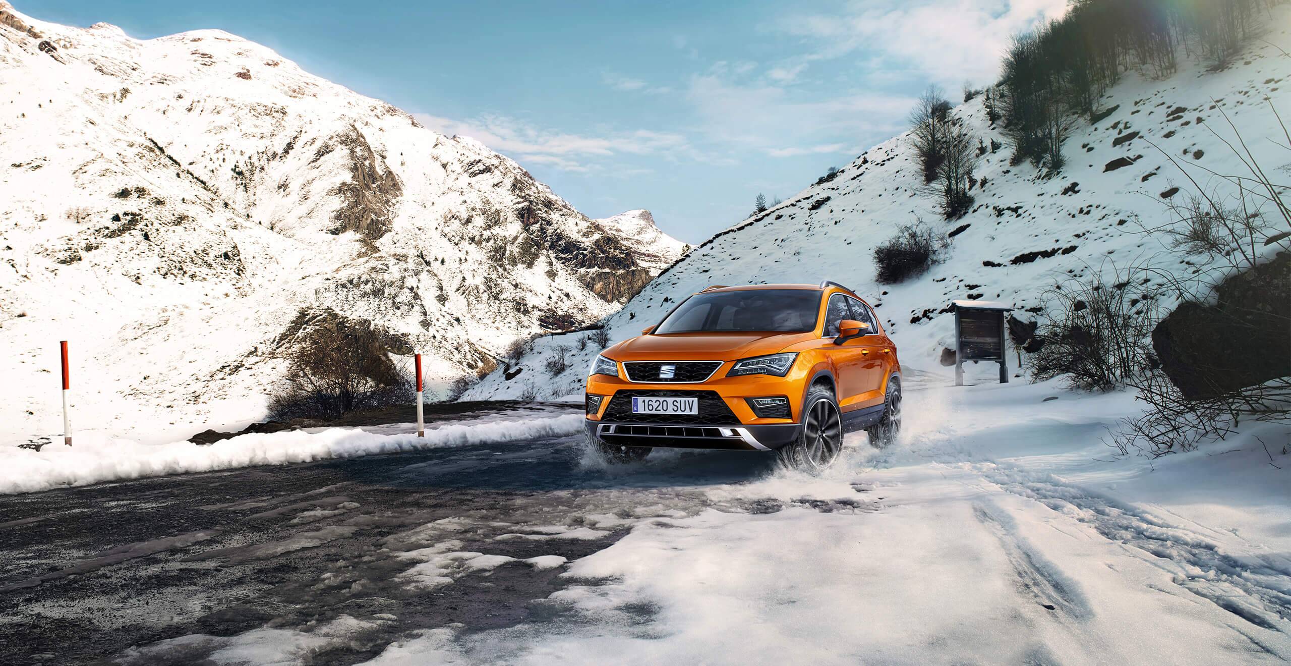 SEAT new car services and maintenance – exterior front action shot of a SEAT Ateca SUV in snowy mountains