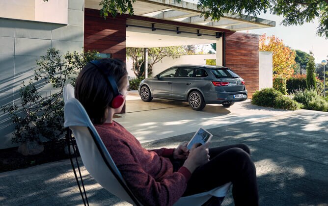SEAT Leon ST parked at home with woman watching in a relaxed scene