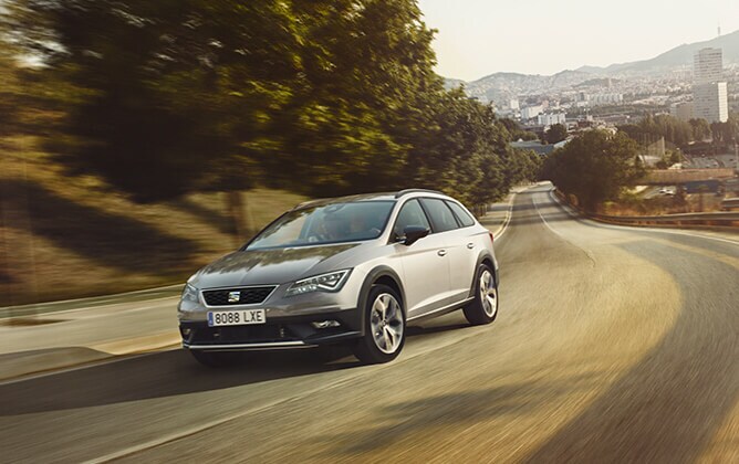 SEAT Leon X-PERIENCE on the road with a city landscape behind